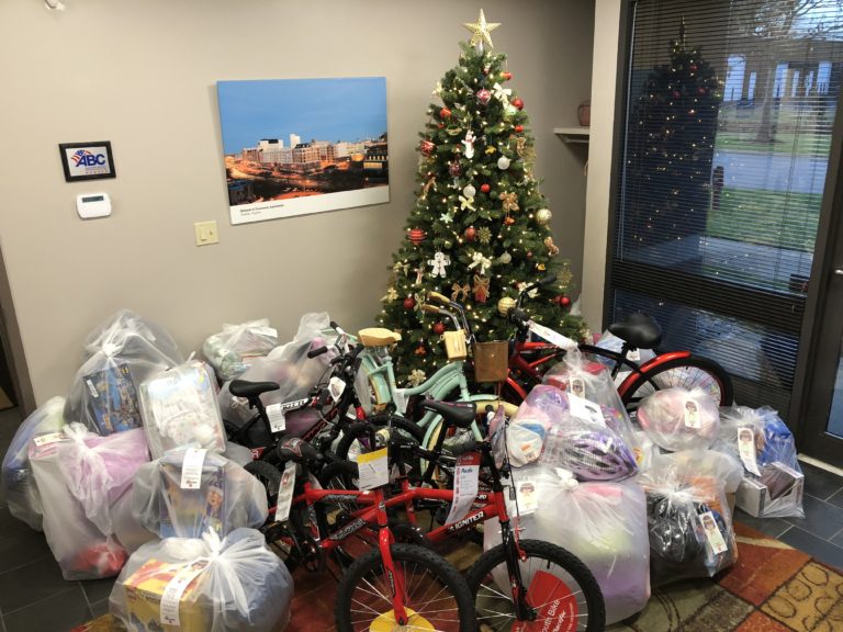 Dozens of donated gifts, including bikes, surround a decorated Christmas tree.