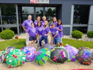 Clancy & Theys employees stand outside their office in matching purple team shirts